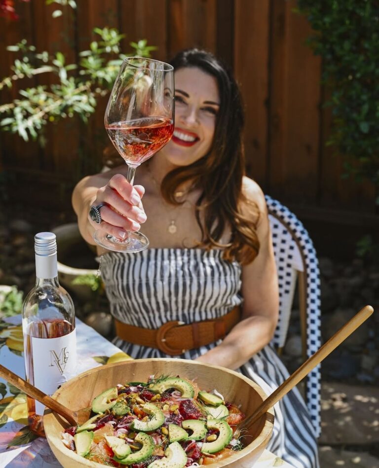 Woman enjoying a glass of wine with a fresh salad while seated at McGrail Vineyards overlooking the vineyard.