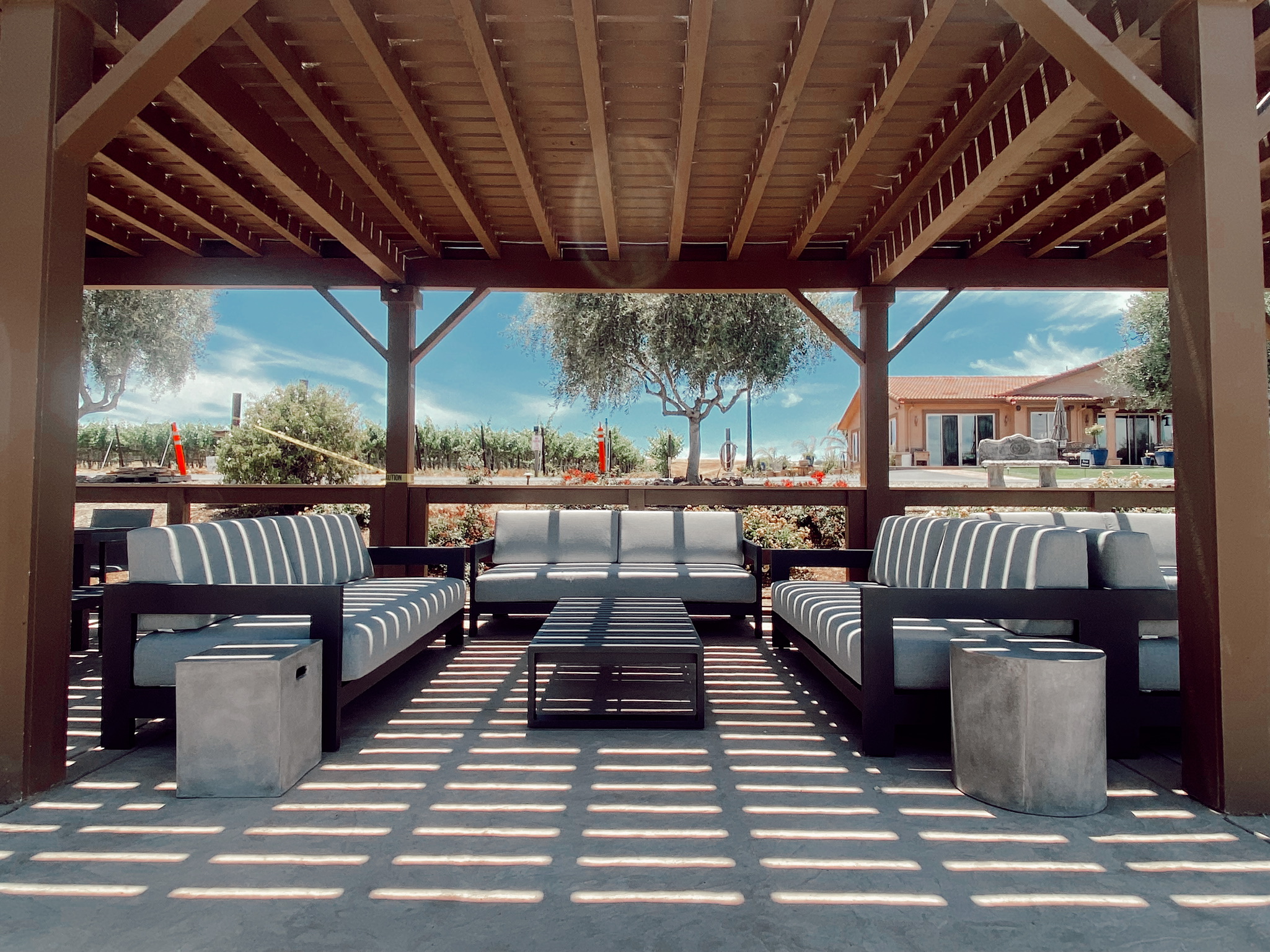 Shaded patio lounge at McGrail Vineyards overlooking rolling vineyard rows and the sunlit hills of Livermore Valley.