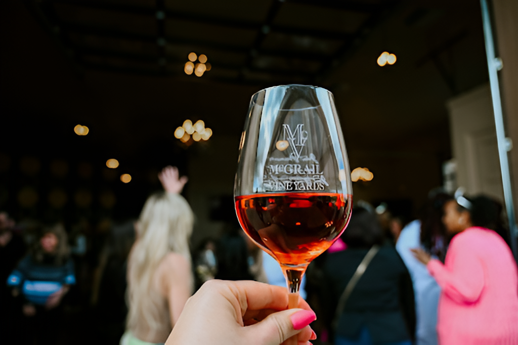 McGrail Vineyards rosé wine glass held during a lively summer tasting event.